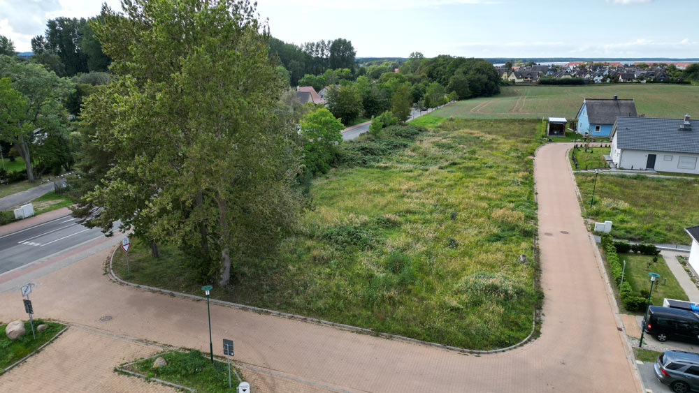 Leeres Grundstück im Quartier Am Kliff, umgeben von Bäumen und Grünflächen, bereit für zukünftige Bauprojekte